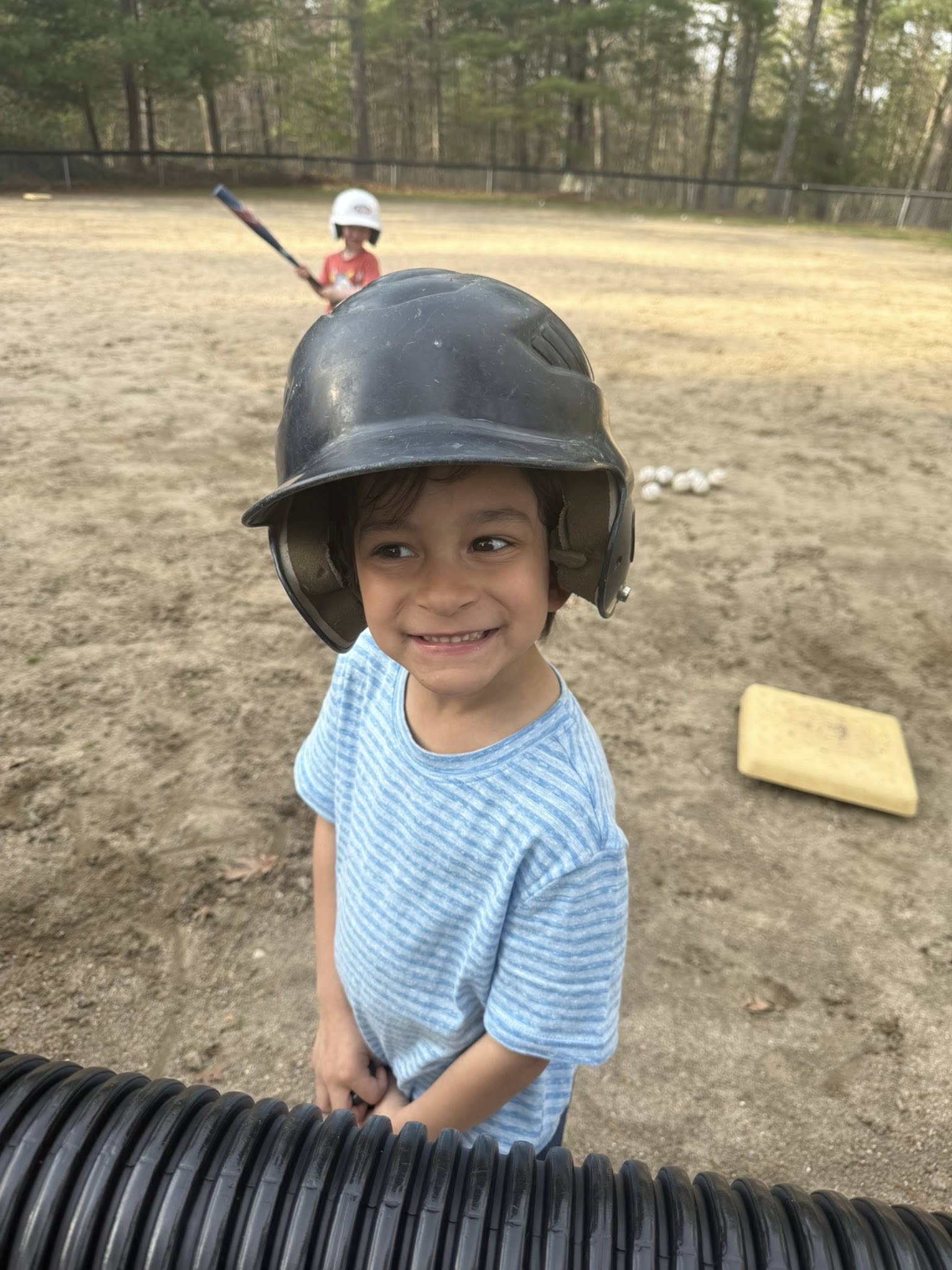 Soren with baseball helmet playing T-ball